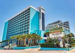 Un hôtel qui se distingue par sa façade bleue imposante, ses nombreux balcons et une enseigne qui fait la publicité des restaurants de la région.