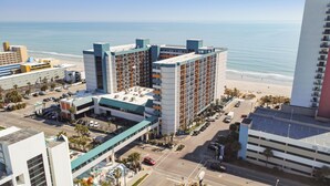A hotel with multiple floors, a parking lot, and a view of the beach. - Ocean Front King Suite Landmark Heated pools (Myrtle Beach)