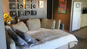 Ein modernes Wohnzimmer mit einer Couch, Kissen, einem Couchtisch und einer Wand, die mit gerahmten Bildern und einem Kakteenbild geschmückt ist.