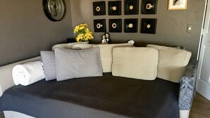 Ein Schlafzimmer mit einem großen Bett, einer Wanduhr, gerahmten Schallplatten und einer kleinen Statue.