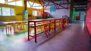 A brightly colored cafeteria with yellow walls, red and yellow chairs, and a long table. - City Hostel (Shymkent)