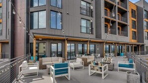 Un espace extérieur moderne, aménagé avec des meubles blancs et bleus, de grandes fenêtres et un balcon.