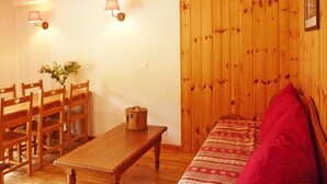 Ein Zimmer mit Holzwänden, einem Holztisch, Stühlen und einer Couch.