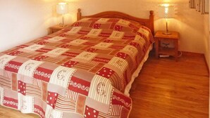 Ein Schlafzimmer mit einem hölzernen Bett, zwei Nachttischlampen und einer gemusterten Bettdecke.