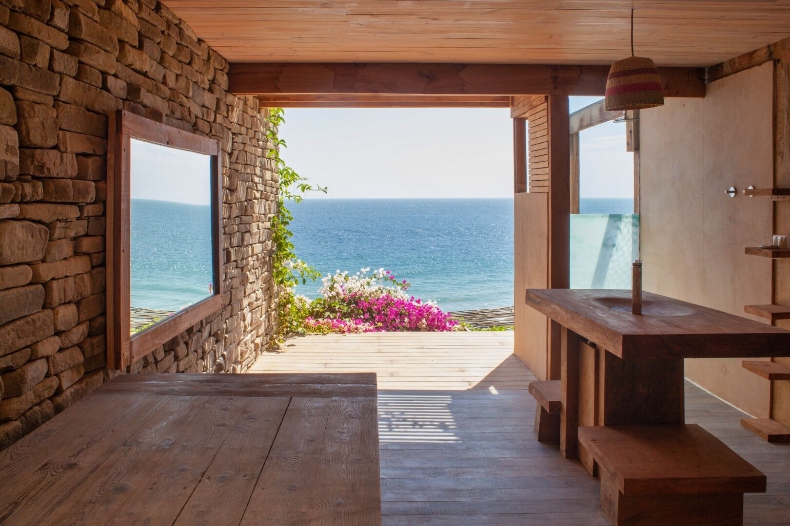 Ein Zimmer mit Steinwand, Holzboden und Blick auf das Meer.