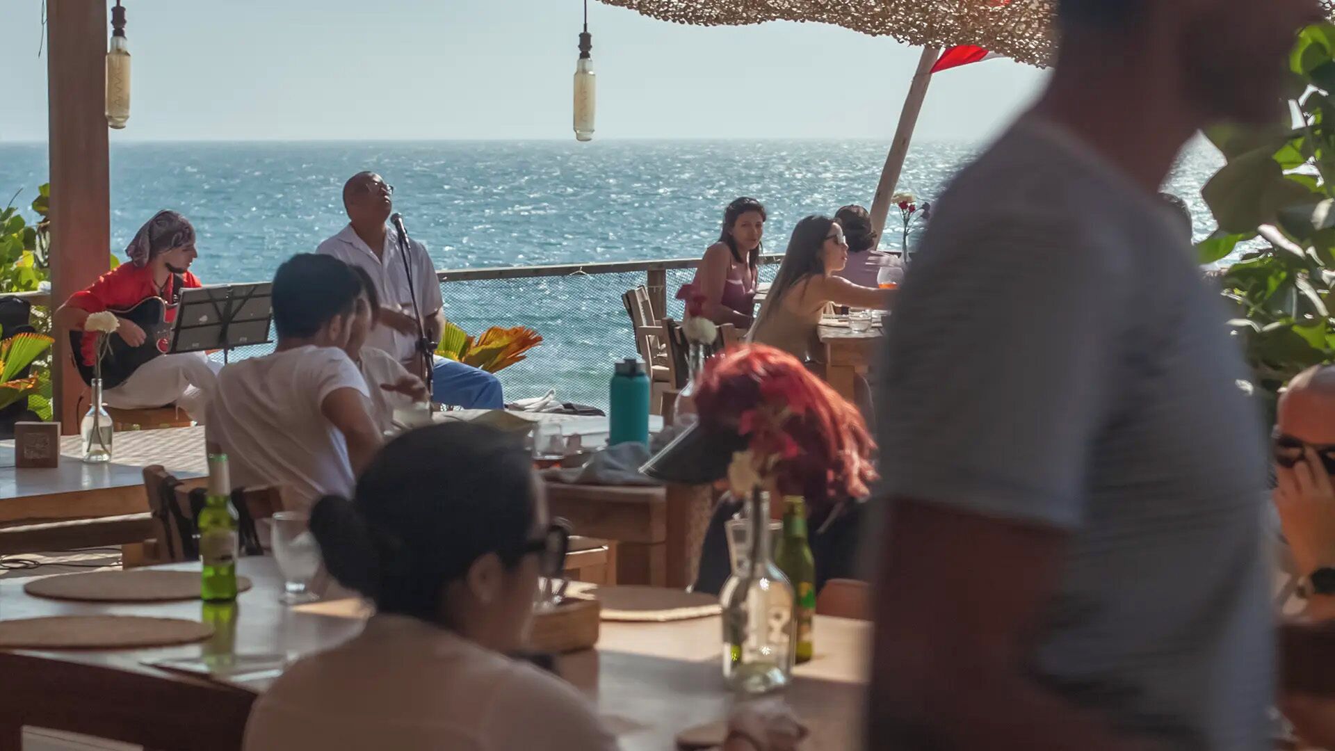 Un grupo de personas sentadas en una mesa al aire libre con vista al océano.