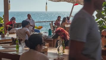 Un grupo de personas sentadas en una mesa al aire libre con vista al océano.