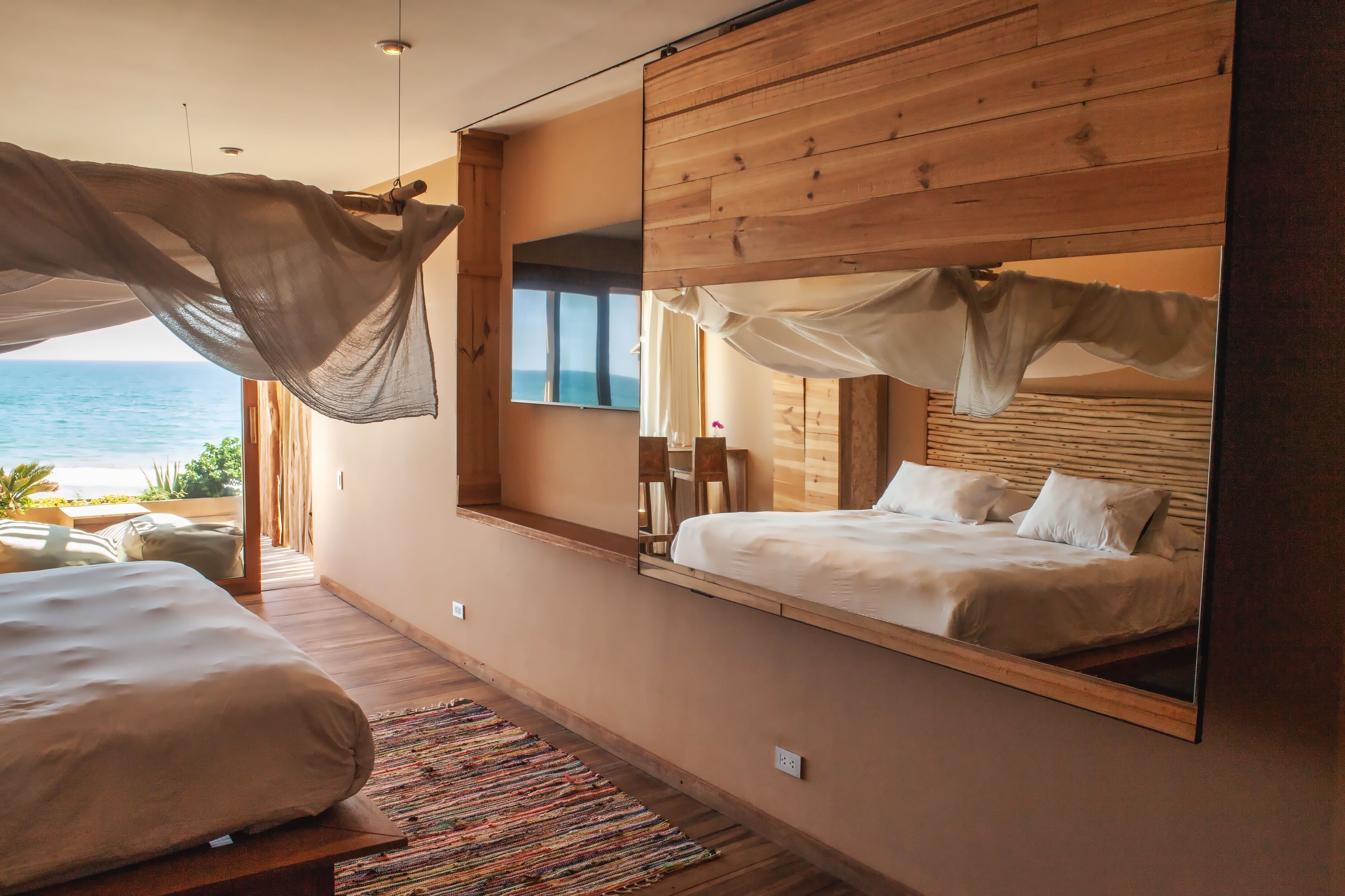 Une chambre avec un grand lit, un miroir et une vue sur l’océan.
