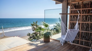 Una terraza de madera con una hamaca y vistas a la playa y al océano.