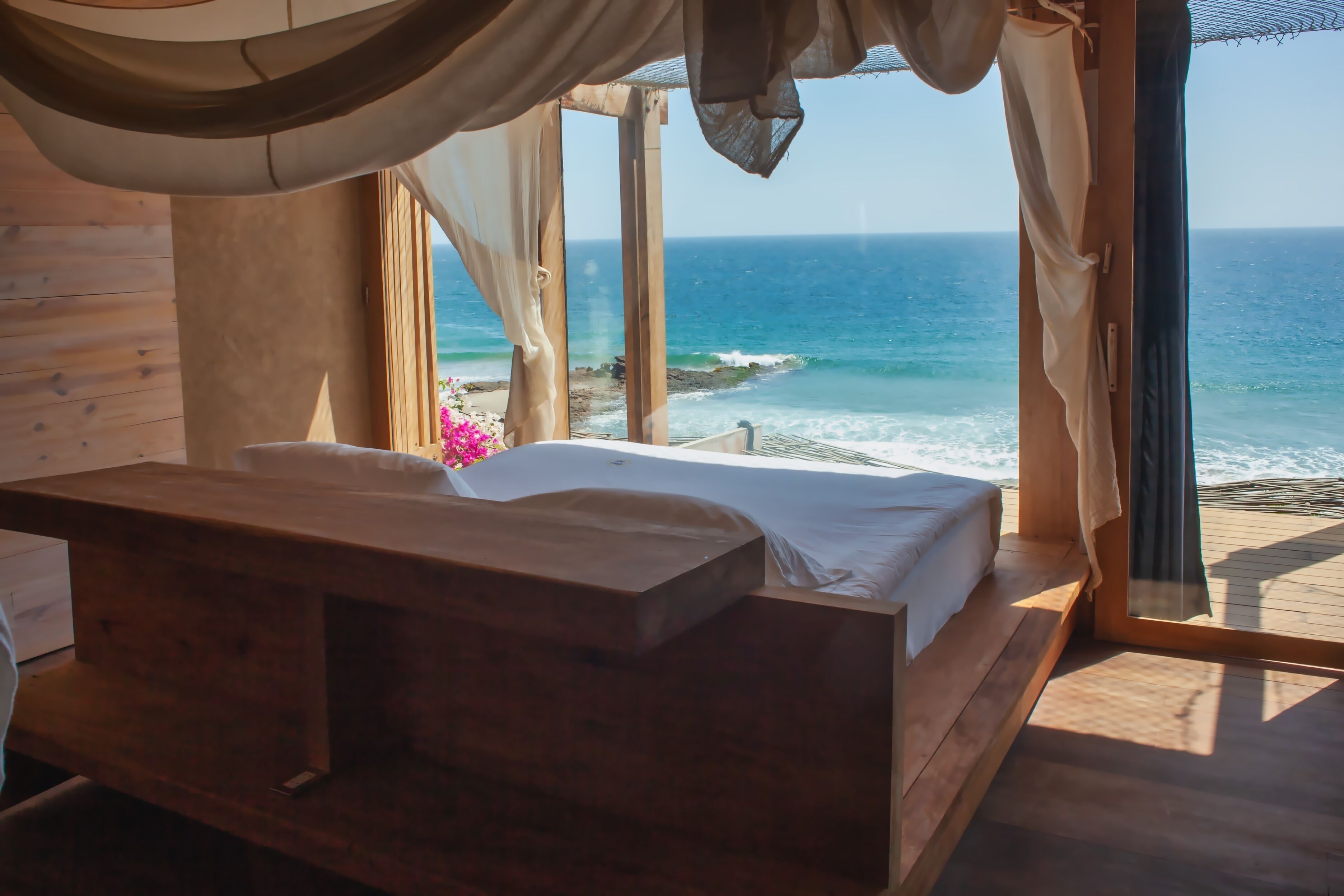A wooden room with a bed and a view of the ocean.
