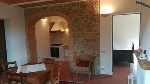 Un espace repas avec un mur en pierre, des meubles en bois et une vue sur la cuisine.
