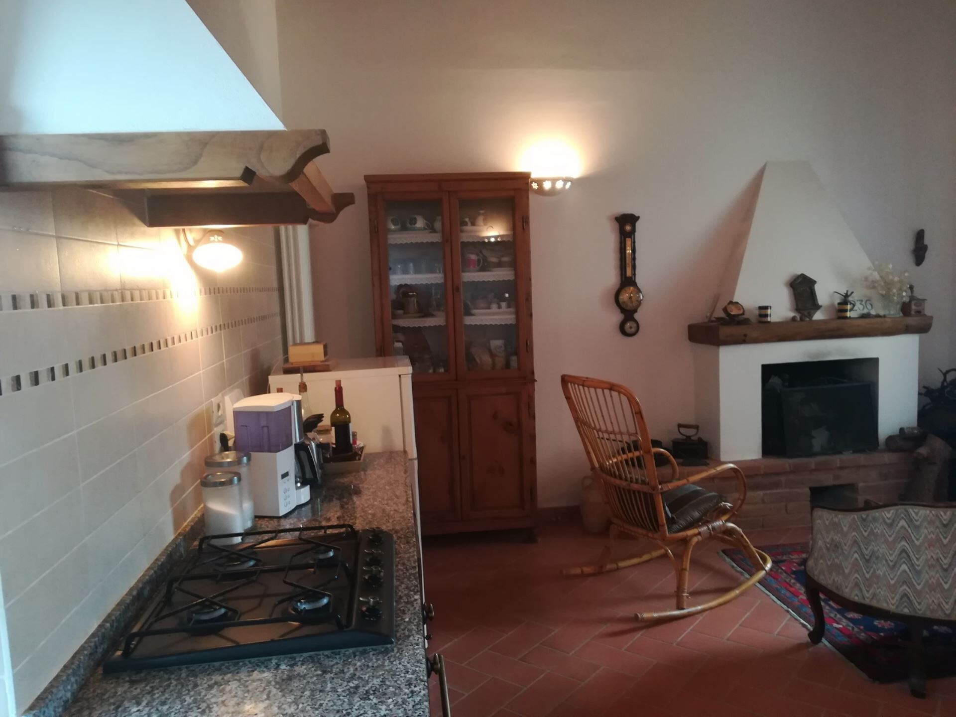 Une cuisine équipée d’une cuisinière à gaz, d’un meuble en bois, d’une chaise en osier et d’une cheminée.