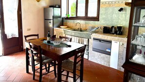 Une cuisine compacte avec un coin repas, comprenant une table en bois, des chaises, un réfrigérateur, un évier et un lave-vaisselle.