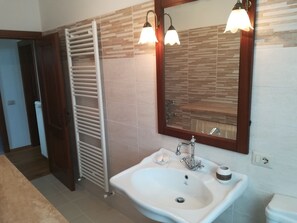 Une salle de bain avec un lavabo blanc, un miroir et un porte-serviettes.