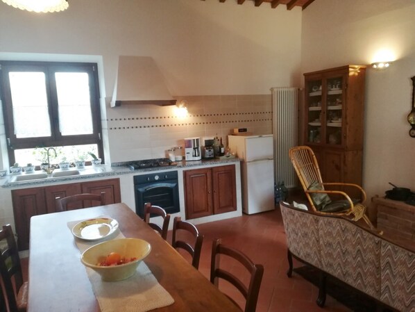 Une cuisine compacte comprenant une table à manger, des chaises, une cuisinière, un four, un réfrigérateur et un placard.
