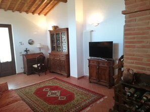Un salon avec un meuble en bois, un téléviseur, un tapis à motifs et un porte-bouteilles.