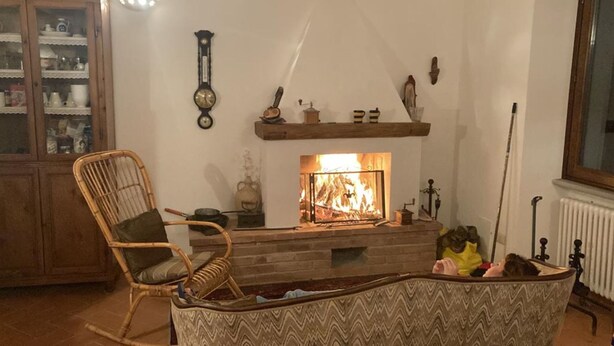Un salon chaleureux avec une cheminée, un meuble en bois et un fauteuil en osier.