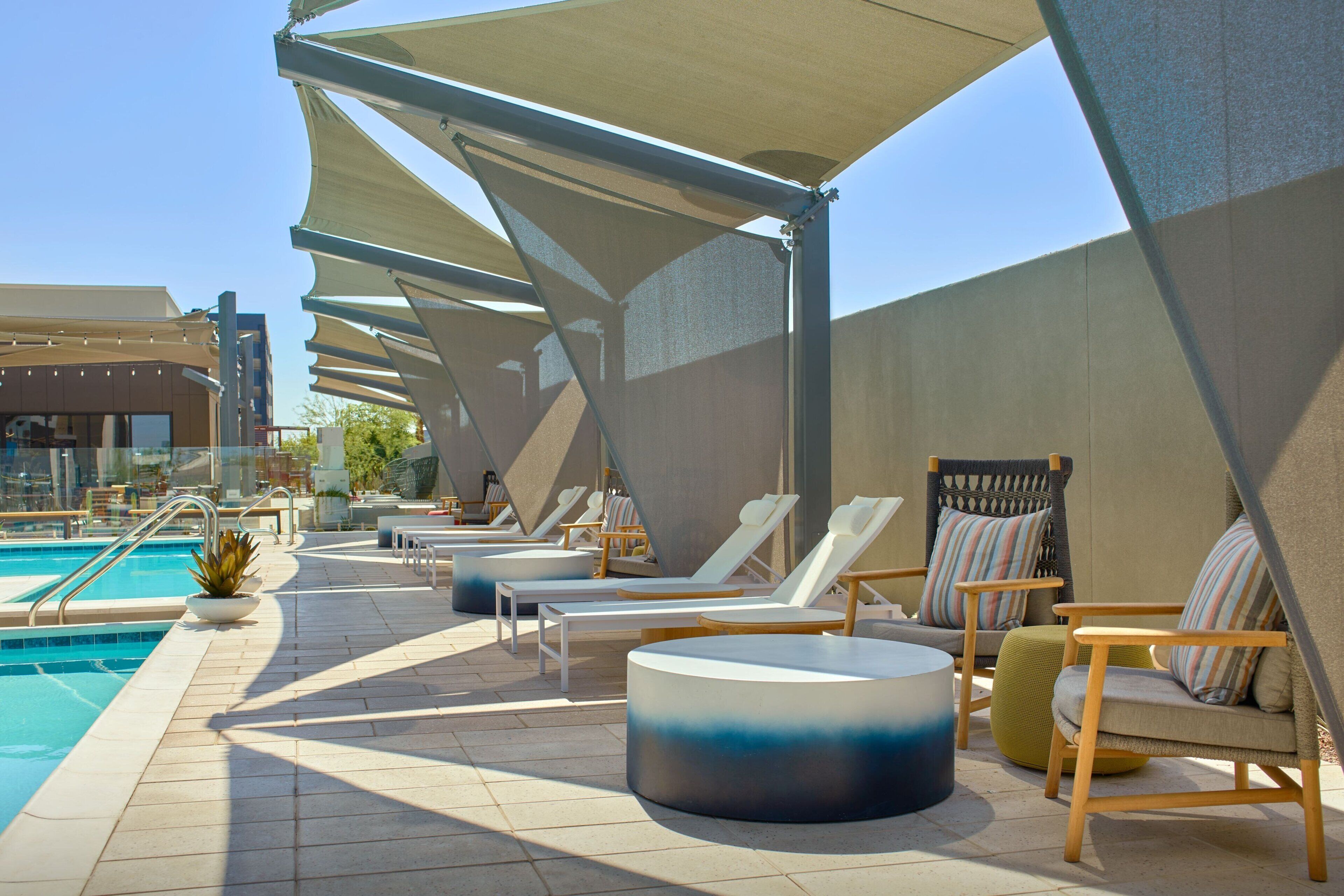 Uma área à beira da piscina com espreguiçadeiras, piscina e guarda-sóis para proteção do sol.