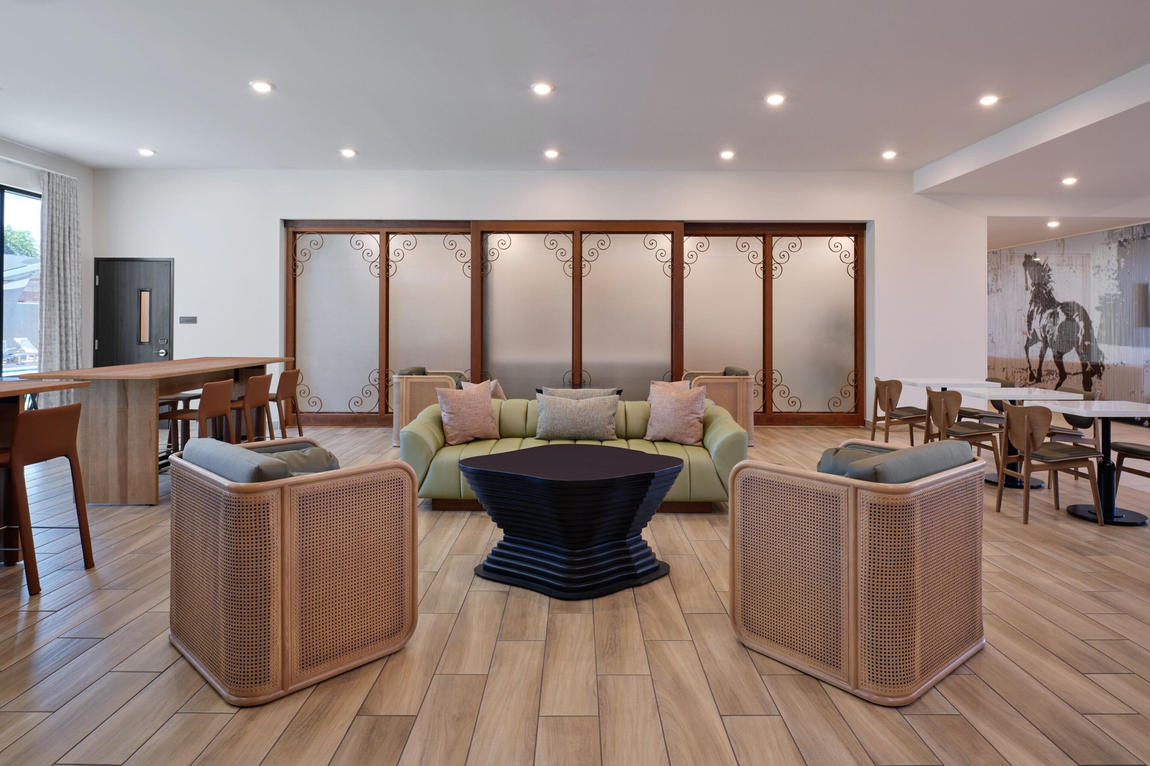 A modern living room with a sofa, two side tables, and a dining area with chairs and a table.