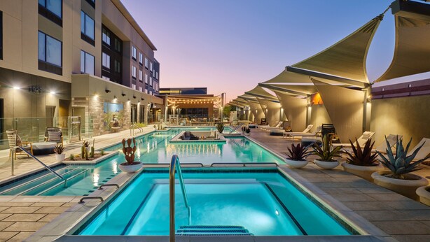 A pool area with multiple swimming pools, lounge chairs, and potted plants. - Towneplace Suites By Marriott Tempe (Tempe)