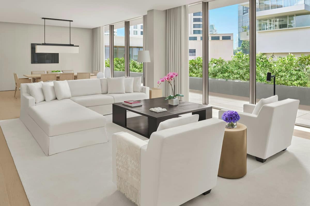 Una sala de estar moderna con un sofá modular, una mesa de centro y vistas de la ciudad a través de amplios ventanales.