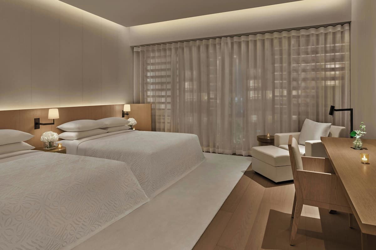 Una habitación de hotel moderna con dos camas, un escritorio y una silla.