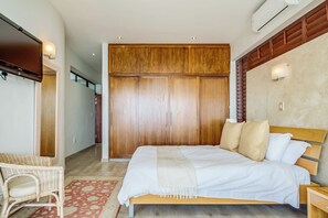 A bedroom with a bed, wooden wardrobe, and a wicker chair.