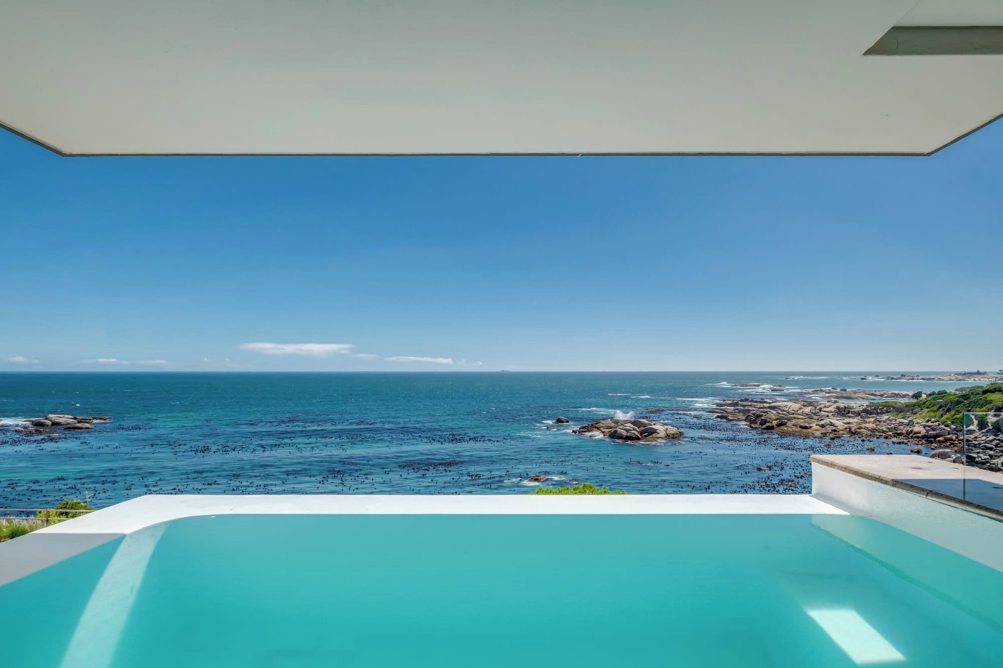 A view of the ocean from a pool with a clear sky.
