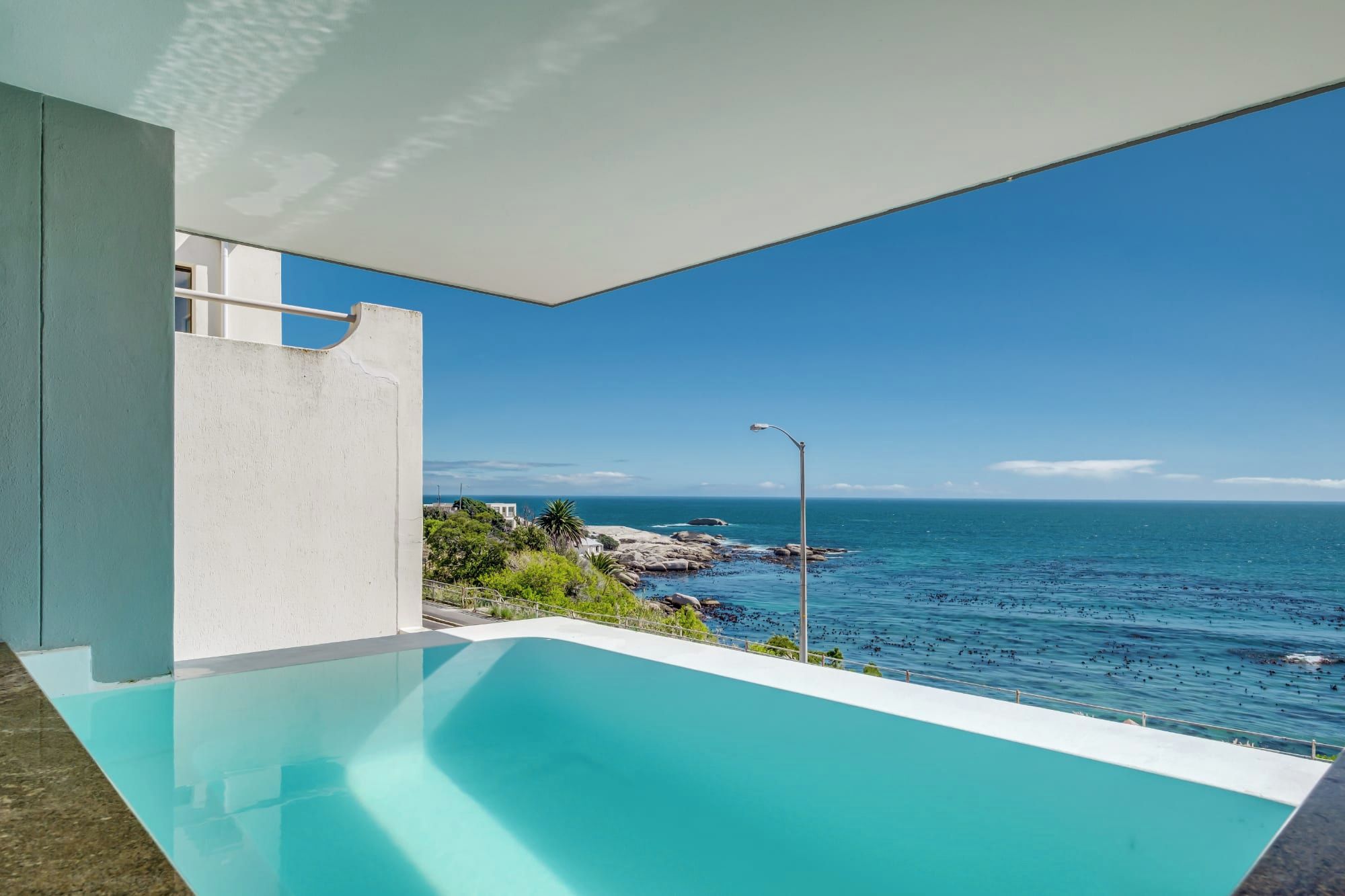 Vista despejada de una piscina con vistas al océano y a la costa rocosa.