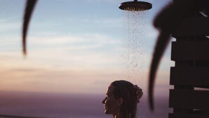 A person standing under a showerhead with water falling on them, overlooking a body of water. - Immaculate Camps Bay Villa w Jacuzzi, Views and Pool Villa Grenache (Cape Town)