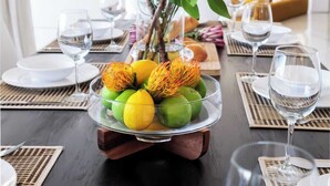 A dining table set with plates, glasses, and a centerpiece of fruits and flowers. - Immaculate Camps Bay Villa w Jacuzzi, Views and Pool Villa Grenache (Cape Town)