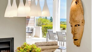Um interior moderno com vista para o mar, uma escultura de madeira e uma suculenta em vaso.