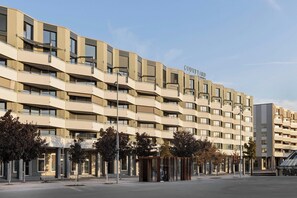 Hotel a più piani dal design moderno, con balconi su ogni piano e una segnaletica ben visibile con il nome dell'hotel.