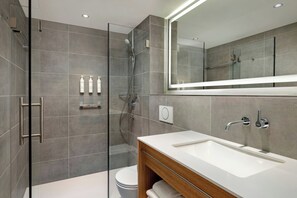 Un bagno moderno con cabina doccia in vetro, lavabo bianco e uno specchio grande.