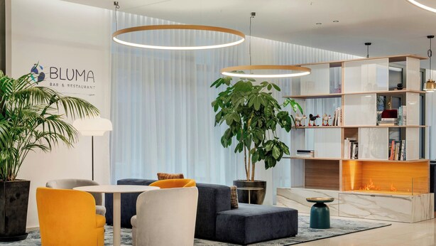 Un área de estar moderna con un sofá, sillas, una mesa y una estantería.
