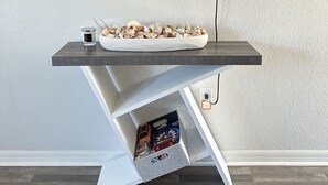 Un mueble de TV moderno con televisor de pantalla plana montado en la pared, una mesita con adornos y un aparador debajo.