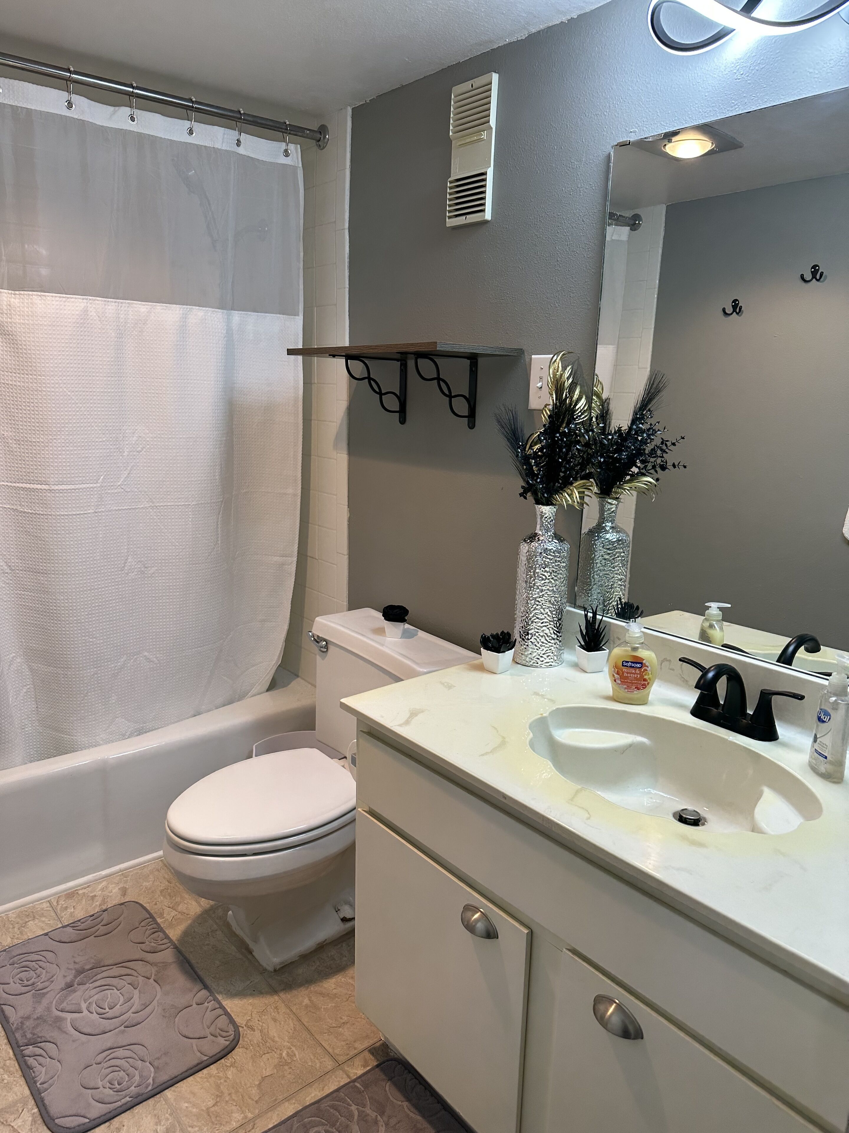 Ein Badezimmer mit Toilette, Waschbecken, Waschtisch und Duschvorhang.
