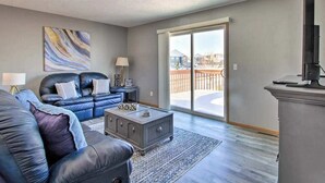 A modern living room with a sofa, coffee table, and a large window with a view of a balcony. - Welcoming West Fargo Retreat w/ Backyard! (West Fargo)