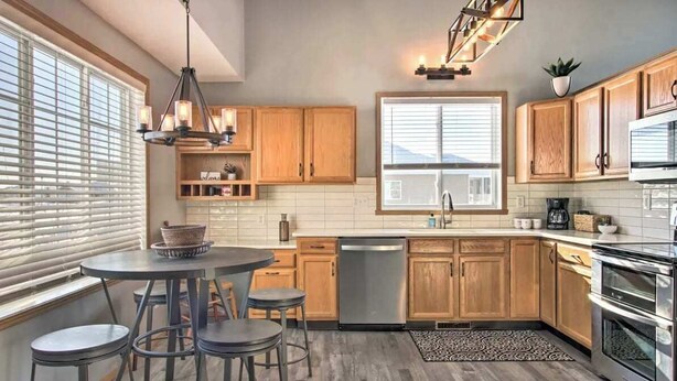 A modern kitchen with wooden cabinets, a stainless steel dishwasher, and a built-in oven. - Welcoming West Fargo Retreat w/ Backyard! (West Fargo)