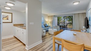 Une cuisine moderne avec des meubles blancs, un plan de travail en granit et un coin repas comprenant une table et des chaises en bois.
