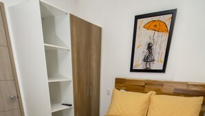 Een slaapkamer met een bed, een kledingkast en een schilderij aan de muur.