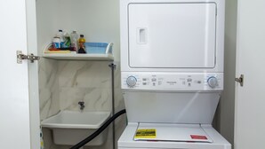 Een kleine wasserijruimte met een wasmachine en een wasbak.