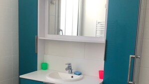 Ein Badezimmer mit einem weißen Waschbecken, türkis-blauen Schränken und einem Spiegel über dem Waschbecken.