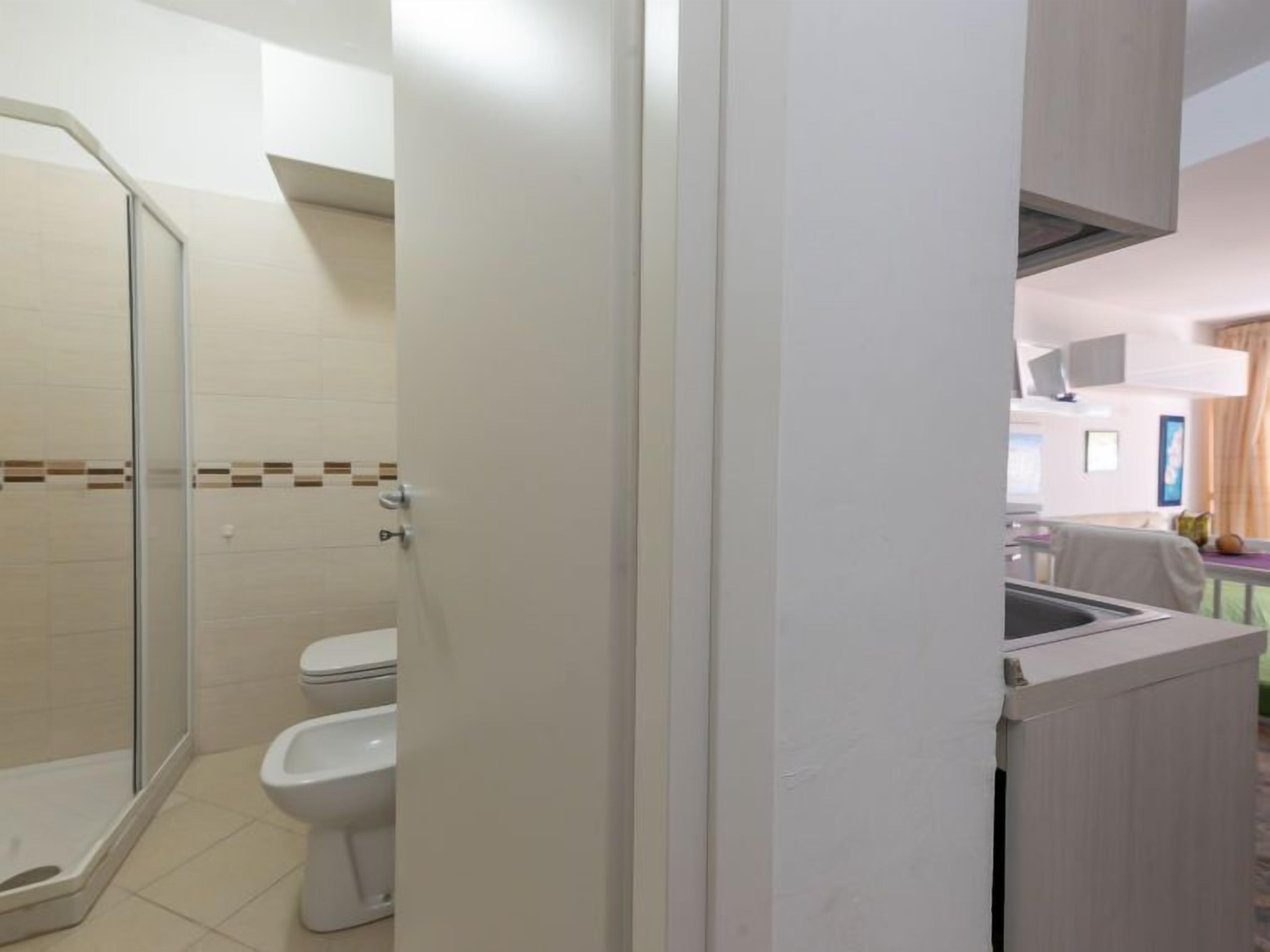 A modern bathroom with a glass shower enclosure, a toilet, and a sink.