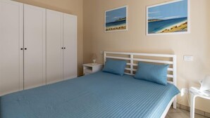 Une chambre à coucher avec un lit, une armoire blanche, deux tableaux et une table de chevet.