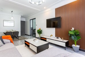 Un salon moderne comprenant un canapé, une table basse, un téléviseur et un coin repas avec des chaises.