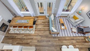 A compact living space with a wooden floor, a sofa, a dining table, and a small kitchen area.