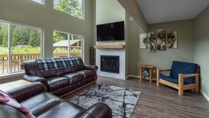A spacious living room with a fireplace, leather sofas, and a television. - Timbers Edge | Quaint Oasis ~ Hot Tub ~ EV Charger (Packwood)
