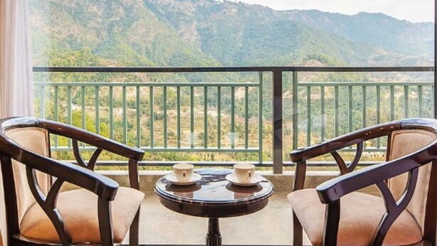 A balcony with two chairs and a small table, overlooking a mountainous landscape. - Captains Paradise (Dhari)