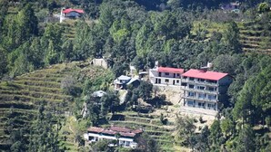 A hillside property with terraced gardens, a large multi-story building with a red roof, and smaller structures. - Captains Paradise (Dhari)